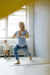 Schwangere Frau mit kleinem Sohn übt Yoga - KNSF05235
