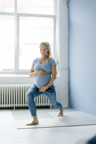 Porträt einer schwangeren Frau, die Yoga praktiziert, lizenzfreies Stockfoto