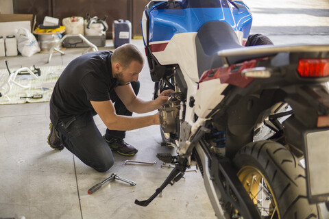 Mechaniker arbeitet an einem Motorrad in der Werkstatt, lizenzfreies Stockfoto