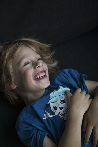 Portrait of happy boy lying on couch stock photo