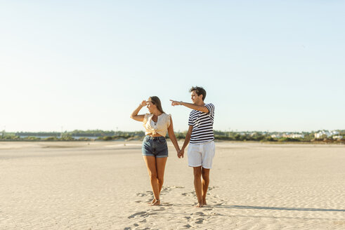 Junges Paar spaziert Hand in Hand am Strand - KIJF02084
