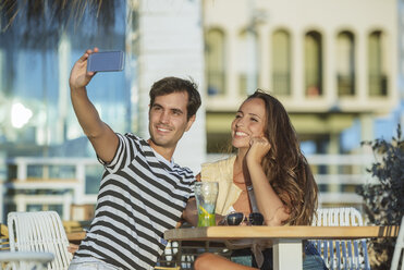 Glückliches junges Paar macht ein Selfie auf der Terrasse einer Bar - KIJF02091