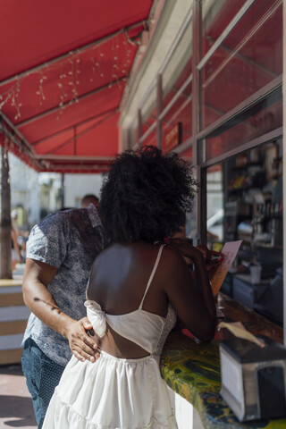 Junges Paar wählt an einem Kiosk eine Speisekarte aus, lizenzfreies Stockfoto