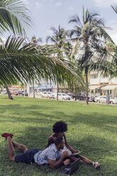 USA, Florida, Miami Beach, junges Paar mit Tablet und Laptop auf Rasen in einem Park - BOYF00873