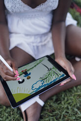 Close-up of young woman in a park drawing on graphics tablet - BOYF00882