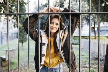 Red-haired smiling woman behind fence - JRFF01926