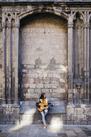 Rothaarige Frau spielt Gitarre in der Stadt, lizenzfreies Stockfoto