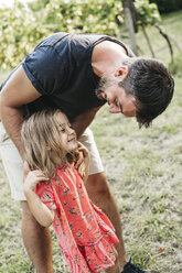 Happy girl standing with father on meadow - HMEF00049