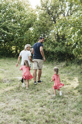 Rückansicht einer Familie mit zwei Töchtern auf einer Wiese - HMEF00052