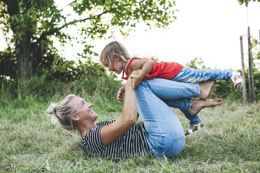 Happy mother playing with daughter on meadow - HMEF00061