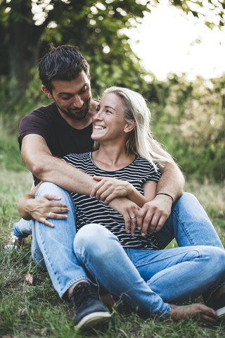Glückliches Paar auf einer Wiese sitzend, lizenzfreies Stockfoto