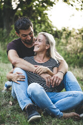 Happy couple sitting on a meadow - HMEF00062