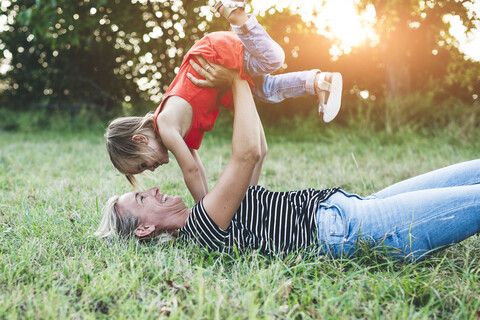 Glückliche Mutter spielt mit Tochter auf der Wiese, lizenzfreies Stockfoto