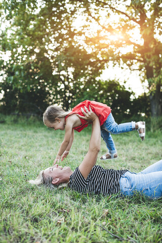 Glückliche Mutter spielt mit Tochter auf der Wiese, lizenzfreies Stockfoto