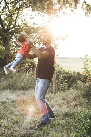 Glücklicher Vater spielt mit Tochter auf der Wiese, lizenzfreies Stockfoto