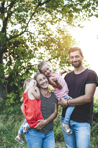 Portrait of happy family with two daughters standing in nature stock photo