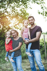 Porträt einer lächelnden Familie mit zwei Töchtern in der Natur stehend - HMEF00071