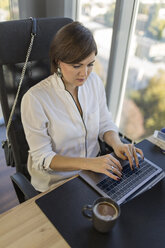 Frau mit Laptop am Schreibtisch im Büro - VGF00093