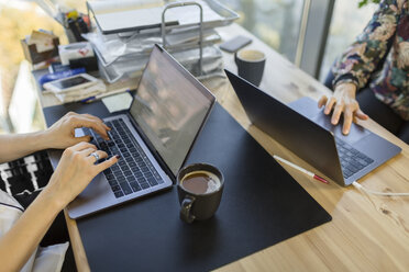 Nahaufnahme von zwei Frauen mit Laptops am Schreibtisch im Büro - VGF00094