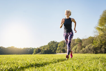 Senior woman running on rural meadow - DIGF05426