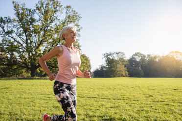 Senior woman running on rural meadow - DIGF05446