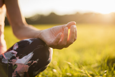 Detail of woman in lotus position on rural meadow at sunset - DIGF05469