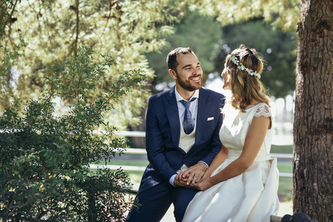 Glückliches Brautpaar, das sich in einem Park an den Händen hält, lizenzfreies Stockfoto