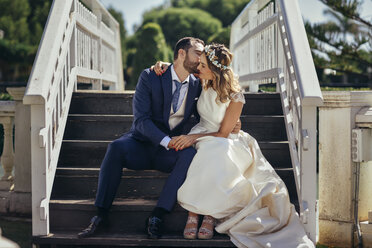 Das Brautpaar sitzt auf der Treppe und genießt seinen Hochzeitstag - JSMF00576
