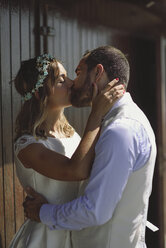 Kissing bridal couple in front of a beach hut - JSMF00583