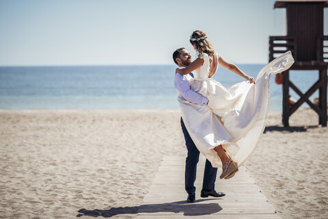 Ein glückliches Brautpaar, das seinen Hochzeitstag am Strand genießt, lizenzfreies Stockfoto