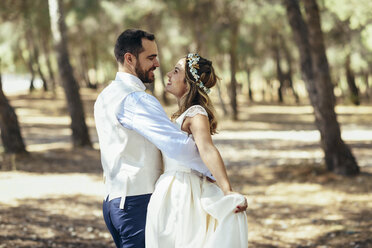 Happy bridal couple dancing together in pine forest - JSMF00588