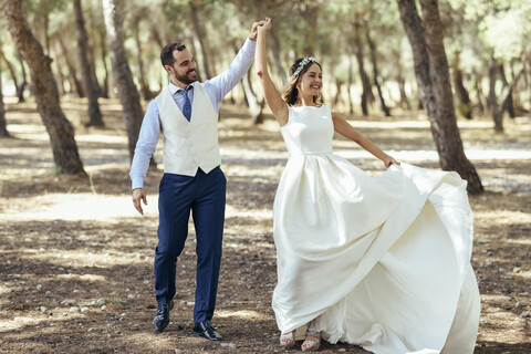 Glückliches Brautpaar tanzt zusammen im Kiefernwald, lizenzfreies Stockfoto
