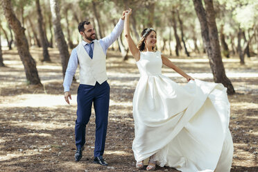 Happy bridal couple dancing together in pine forest - JSMF00589