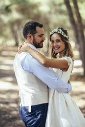 Portrait of happy bride dancing with her groom in pine forest - JSMF00591