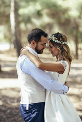 Happy bridal couple dancing together in pine forest - JSMF00592