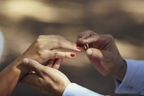 Bräutigam steckt Ehering an den Finger der Braut, Nahaufnahme - JSMF00594
