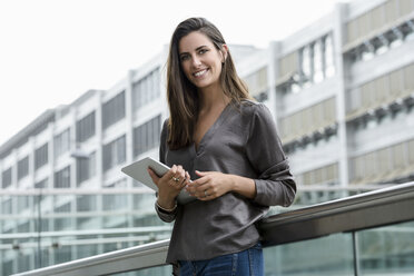 Portrait of smiling young businesswoman with digital tablet - BMOF00079