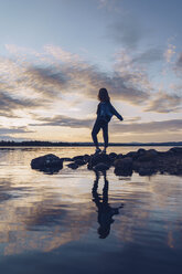 Junge Frau am Inari-See stehend, mit ausgestreckten Armen, Finnland - RSGF00099
