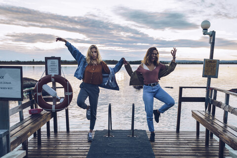 Two girl friends standing on one leg on a pier at Lake INari, Finland stock photo