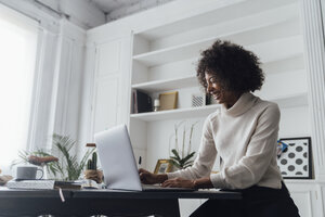 Mittlere erwachsene Frau, die in ihrem Heimbüro arbeitet und einen Laptop benutzt - BOYF00901