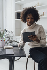 Mid adult freelancer sitting at her desk, working with laptop and digital tablet - BOYF00933