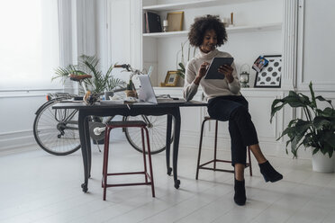 Mid adult freelancer sitting at her desk, working with laptop and digital tablet - BOYF00936