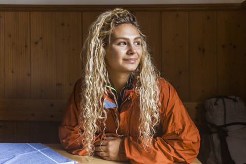 Junge Frau sitzt in einer Berghütte und macht eine Pause vom Wandern, lizenzfreies Stockfoto