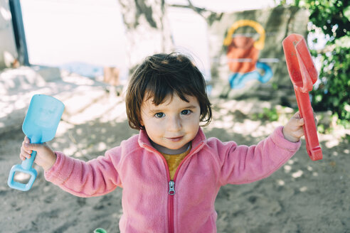 Baby girl playing with sand and shovels outdoors - GEMF02508