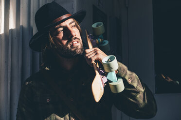 USA, New York City, portrait of bearded man with skateboard wearing black hat - OCMF00098