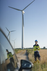 Lächelnder Ingenieur auf einem Feld in einem Windpark - GUSF01307