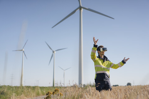 Engineer standing in a field at a wind farm wearing VR glasses stock photo