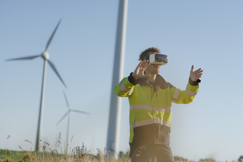 Ingenieur mit VR-Brille auf einem Feld in einem Windpark, lizenzfreies Stockfoto