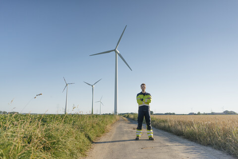 Engineer standing on field path at a wind farm stock photo