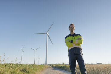 Ingenieur steht auf einem Feldweg in einem Windpark - GUSF01318